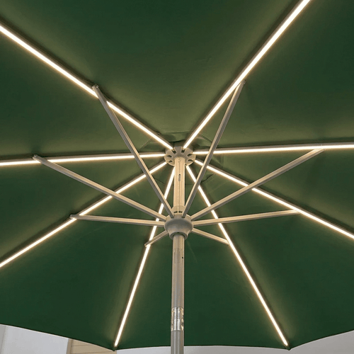 A close-up view from underneath a green patio umbrella, showing the silver metal ribs and integrated LED strip lights glowing along the canopy.
