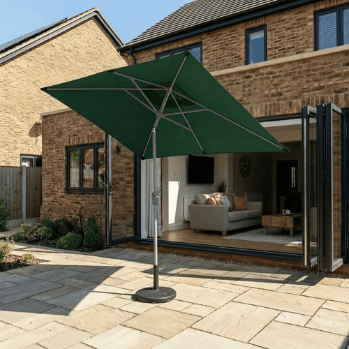 Halo 3m x 2m rectangular centre pole parasol in green, canopy tilted to angle the shade across a stone patio