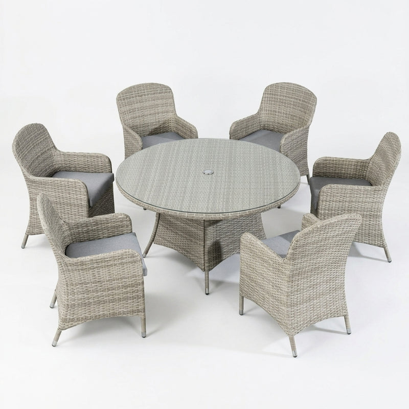 A 7-piece outdoor patio dining set featuring a round woven wicker table and six matching armchairs with gray cushions, shown on a seamless white background.