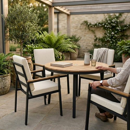 Outdoor patio setting with wooden table and chairs on a stone patio.