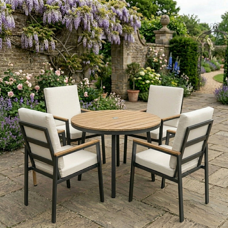 Outdoor patio set with round table and four chairs in a garden setting.