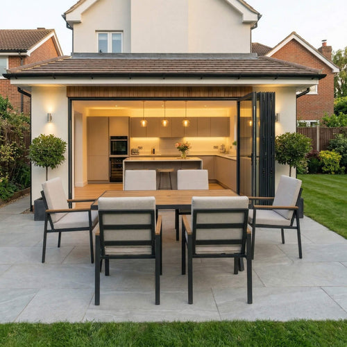 Outdoor patio area with dining table and chairs in front of a modern house.