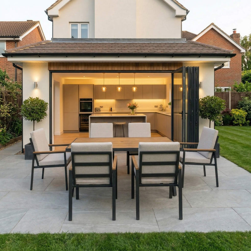 Outdoor patio area with dining table and chairs in front of a modern house.