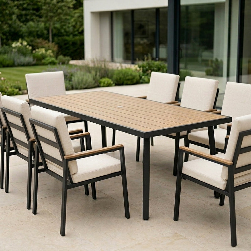Outdoor dining set with a wooden table and chairs with white cushions on a patio.