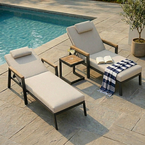 Outdoor patio furniture set with lounge chairs and a small table by a pool.